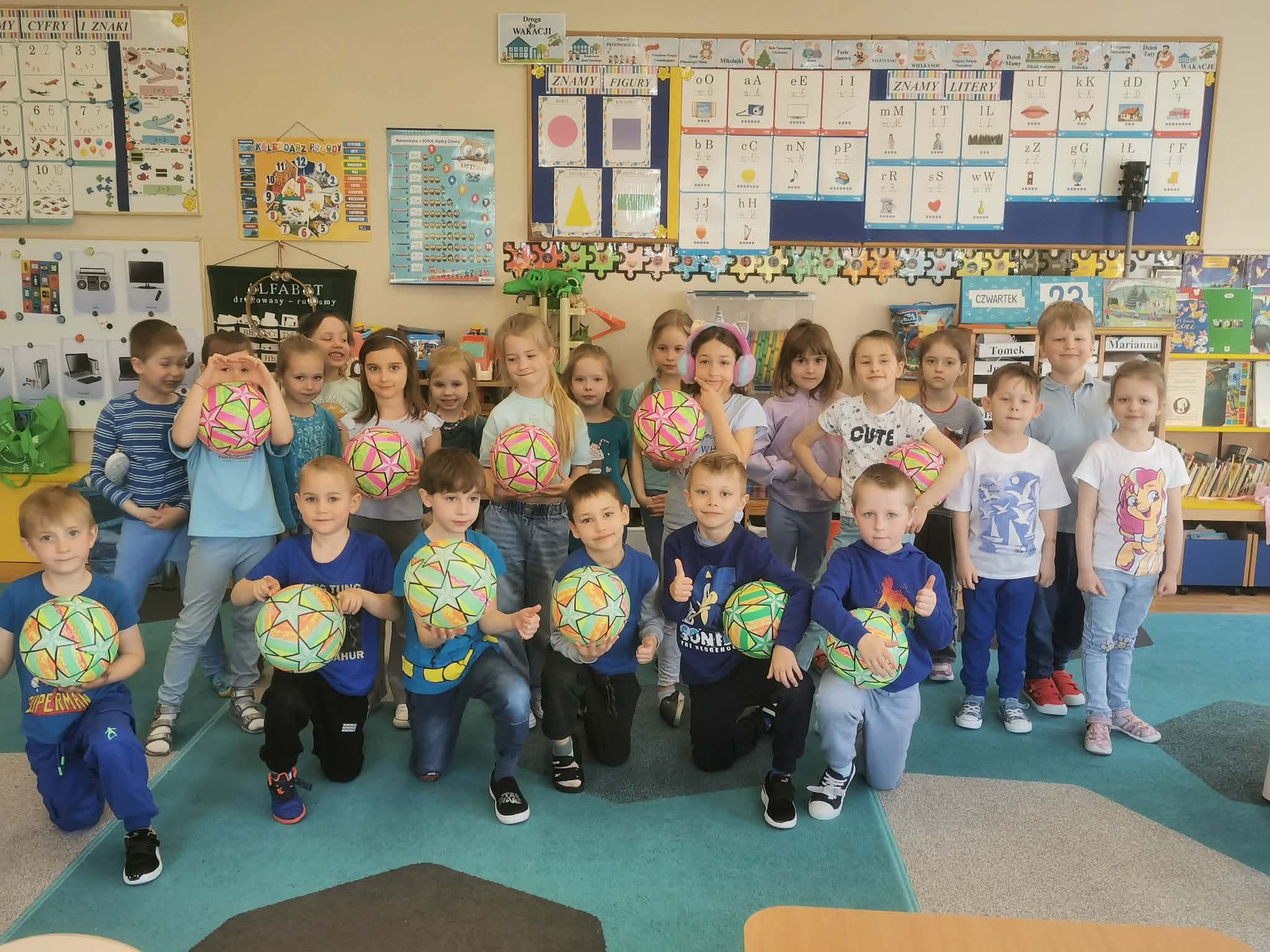 Grupa dzieci trzymających piłki &ndash; nagrody od nauczycielek.