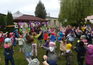 Dzieci ustawione przed sceną podnoszą ręce do góry