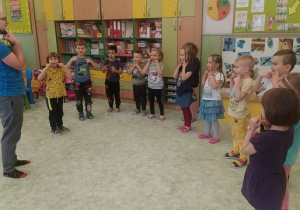 Dzieci z Panem Miłoszem pokazują uśmiechnięte buźki.