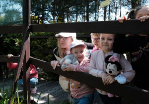Dzieci i jedna z mam pozują do zdjęcia na drewnianym mostku.
