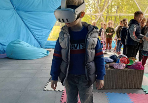 Dziecko stoi i obserwuje dinozaury przez google VR.