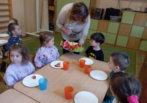 Pani oferuje chłopcu różne owoce.