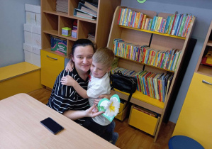 Chłopiec przytula się do swojej mamy i wręcza jej serduszko i kwiatka.