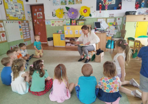 Pani adwokatka czyta książkę dzieciom (zgromadzonym na dywanie).