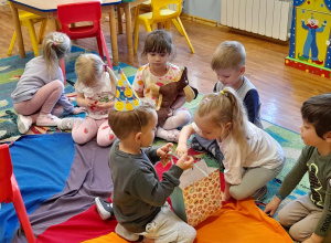 Jubilat częstuje dzieci cukierkami.