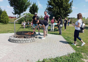 Ognisko - trzech tatusiów piecze kiełbaski.