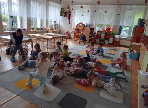 Dzieci leżą na dywanie i słuchają bajki dla dzieci.
