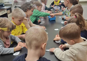 Dzisiaj stoją przy stole i kolorują papierowe listki.