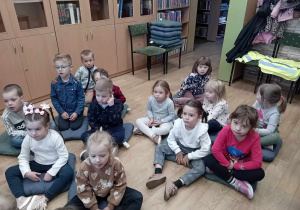 Przedszkolaki siedzą na poduszkach i słuchają ciekawostek o jesieni.