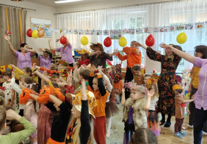 Dzieci (w jesiennych przebraniach) i pracownicy przedszkola podczas wesołej zabawy na Balu Jesieni.