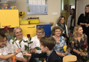 Chłopiec wręcza Pani drobny upominek z okazji Dnia Nauczyciela.