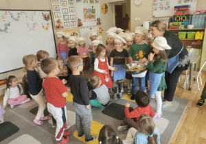 Grupa dzieci częstuje młodszych kolegów z przedszkola wykonaną przez siebie sałatką.