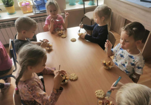 Grupa dzieci je wykonaną przez siebie sałatkę owocową.
