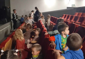 Dzieci siedzą na krzesłach w kinie czekając na film