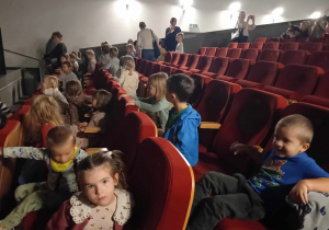 Dzieci siedzą na krzesłach w kinie czekając na film