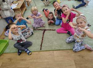 Grupka dzieci z ułożoną z kasztanów literką "T".