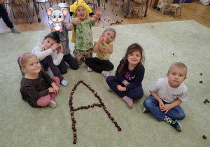 Grupka dzieci z ułożoną z kasztanów literką "A".