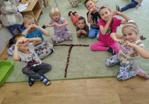 Grupka dzieci z ułożoną z kasztanów literką "T".