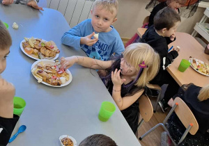 Dzieci przy stolikach podczas słodkiego poczęstunku.