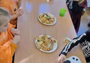 Dzieci przy stolikach podczas słodkiego poczęstunku.