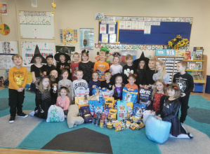 Dzieci pozują do zdjęcia z zebraną karmą dla zwierząt.