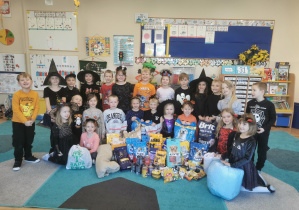 Dzieci pozują do zdjęcia z zebraną karmą dla zwierząt.