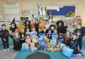 Dzieci i wychowawca grupy pozują do zdjęcia z zebraną karmą dla zwierząt.