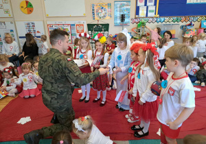 Żołnierz wręcza dzieciom nagrody za udział w konkursie.