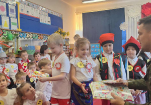 Żołnierz wręcza dzieciom nagrody za udział w konkursie.