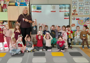 Dzieci wraz z panią Naczelnik prezentują wykonane przez siebie kokardy narodowe.