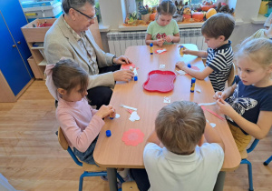 Pan Burmistrz wraz z dziećmi wykonują kokardy narodowe.