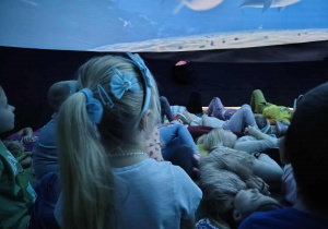 Przedszkolaki podziwiają film, wyświetlany na powierzchni sferycznej kopuły.