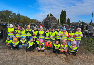 Dzieci pozujące do grupowego zdjęcia na tle zbiorowej mogiły wojennej żołnierzy Wojska Polskiego poległych we wrześniu 1939 r. oraz cywilnych ofiar terroru hitlerowskiego.
