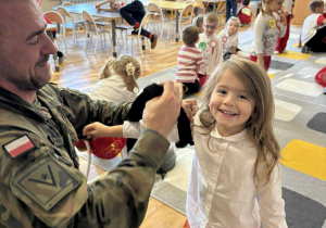 Żołnierz "zakłada" dziecku opaskę uciskową.