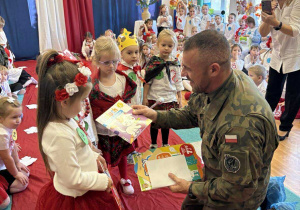 Żołnierz wręcza dzieciom drobne prezenty.