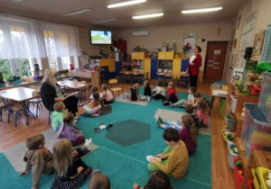 Dzieci (zgromadzone w kole na dywanie) podczas zajęć z pedagogiem i psychologiem.