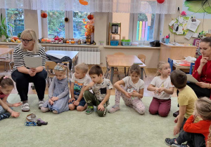 Dzieci (zgromadzone w kole na dywanie) podczas zajęć z pedagogiem i psychologiem.