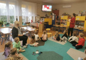 Dzieci (zgromadzone w kole na dywanie) podczas zajęć z pedagogiem i psychologiem.