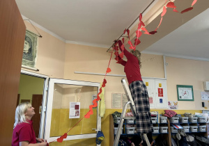 Dwie Panie wieszają pod sufitem łańcuch.