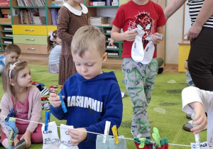 Chłopiec przypina skarpetki do sznurka.