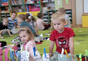 Dzieci oglądają pary skarpetek przypięte do sznurka.