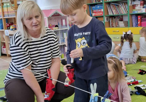 Chłopiec przypina skarpetki do sznurka.