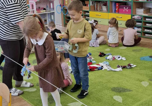 Dziewczynka przypina skarpetki do sznurka.