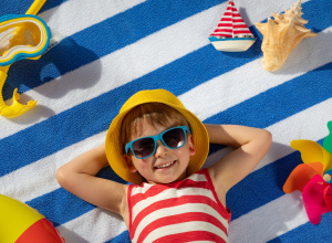 Kolorowa fotografia przedstawiająca uśmiechnięte dziecko na plaży.