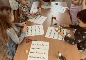 Dzieci wykonują zadania na kartach pracy- zróżnicowane zależnie od wieku.