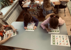 Dzieci wykonują zadania na kartach pracy- zróżnicowane zależnie od wieku.