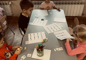 Dzieci wyklejają kuleczki z plasteliny, którymi wypełniają białe punkty w postaci misia.