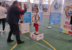 Dziewczynka na podium przybija "piątkę" z organizatorem zawodów.