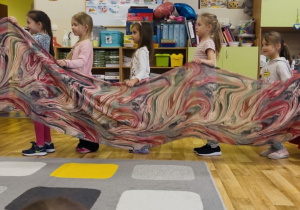 Dwie dziewczynki w trakcie tańca z kolorową chustą.