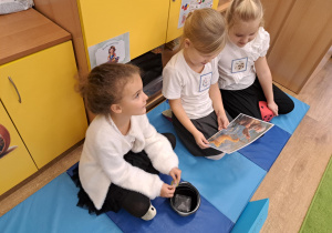 Trzy dziewczynki przyglądają się ilustracji.